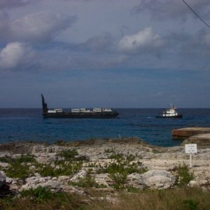 Hunky Dory traveled from Tampa to Grand Cayman on a cargo ship, then from Grand Cayman to Little Cayman on the weekly barge that is pulled by a tugboat.  This is our first peek at her, sitting regally on the barge.