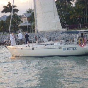 A sunset marriage on the front of a sailboat. He should jump now while he still has a chance