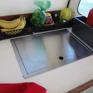Media 'Princess butane drop-in stove, flat stainless lidded version (other version has wooden cutting board that sits on top).' in album 'Sink cover board while varnishing.  I made a similar one (sans hole) for the cutout where the Wallas used to be.  It's surprisingly handy to be able to remove it to work on things (wiring etc.) under the galley, although I may eventually replace the whole galley counter and if so will likely make it a solid piece except for the sink cutout.'