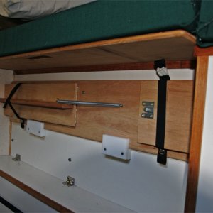 Media 'Bed support for the starboard bed is stowed on the  port-side box. Note the extender support  holding the port extender cushion. It can be quickly slid back under the lid to allow use of the original cushion for the 2 position commuter seat. The starboard bed support rests on a wood block at each end and is captured by the slotted fingers; it is rock solid with the leg extended. The storage box with lid is 40 inches long and holds kitchen items.' in album 'Port and Starboard Beds looking aft. The kitchen storage pocket is removed from the helm seat back and snapped to the cabin door when the starboard bed is setup.'
