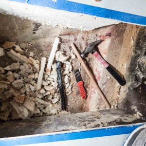 Media 'I used a metal pipe with one end sharpened as a coring tool to remove the foam under the portable toilet storage area. The wooden dowel is used to push the foam core plugs out of the pipe. The end goal was a tunnel that passes under the inspection hole and to the other side, just forward of the cored hull bottom, for battery cables to pass through.' in album 'My boat had no inspection hole and no obvious hole of any kind where foam could have been injected. I decided to drill an inspection hole to see what was in there.'