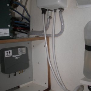 Aft wall of the under sink cabinet showing the hot water faucet "fix" by just tossing the nylon fitting and clamping directly to the faucet threads after heating the hose.