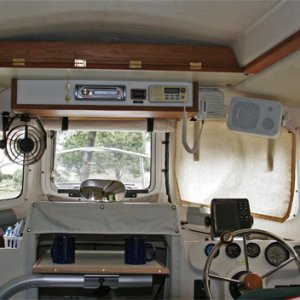 Added overhead console with AM/FM/CD/Aux,speakers' VHF, rode counter and storage door. Upper shelf provides needed storage with quick access behind teak panel. Swivel table can be moved in 3 axes to form dining table, chart/laptop surface, galley table or it can be placed in vertical position to stow