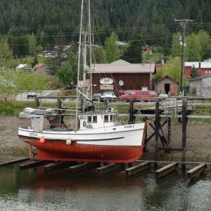fishing boat on tidal grid getting new coat of bottom paint at Hoonah marina