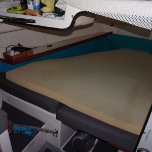 port bulkhead removed to open up the V berth.  Note 4" memory foam pad on top for comfort!  We have also put pads on the side of the bunk and under the bunk to eliminate any condensation there.  There is a teak grab rail on the upper forward area under the windshield.  In back of that is another dual outlet USB charger.  There ia the Maestro fan in the outboard part of the aft part of the V berth.  The control for this (speed, light --white or red) is located just inside on the overhead.  The fan is easily adjusted from either in the bunk or from outside.  Same for the other side.  
The cutout opens up the cabin, and makes entry into the bunk much easier.