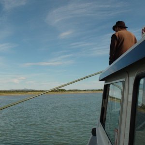 Poling boat with motors up in shallow water entering Lake Labarge