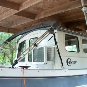 Media 'Exterior view of AC. Exterior panel above AC is cut to the same size as the original window and painted white. A cover for the AC will be made in the future. View of the shelter, constructed for a previously owned pontoon boat did not allow enough overhead clearance to consider a roof top AC.' in album 'Dometic CF-50 fits easily in V berth with filler cushion removed. Height almost same as bunk height and refrig will support our weight as we enter/depart berth. We have never used this area for the head. It is kept on deck during day and placed just inside cabin door at night.'
