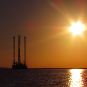 Oil rig moving down the ship channel at sunset