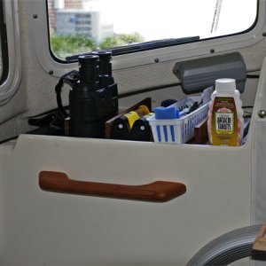 Port console shelf is divided by teak kitchen drawer dividers to keep stuff organized. Grippy mats in each section keep stuff from shifting around. The bride requested a grab handle.