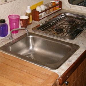 Sink with pressure water system and alcohol stove with cover used as extra counter space.