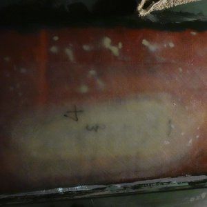 I sanded the paint off the patch and surrounding area and built up the area with epoxy resin and four layers of 1708 until the contour of the patch matched the surrounding area of the hull. The white spots are thickened eopxy under the glass, that I used to fill voids in the old repair (which will be removed from the top in the next step).
