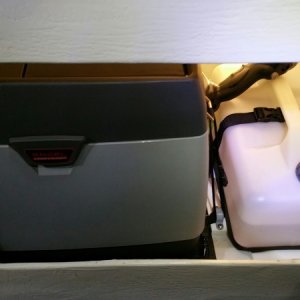 We put an Engel MD14F freezer under the helm seat in the storage compartment. So far, we are storing rain gear and some larger kitchen goods behind it and access is good enough for those items.