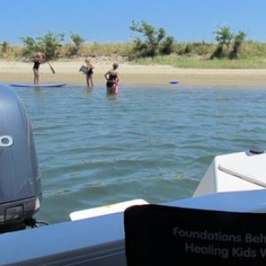 on the hook in West Neck Harbor on Shelter Island New York,Ginny paddle boarding on a borrowed board while Jess and Becky watch and swim. All three devil sisters in one photo