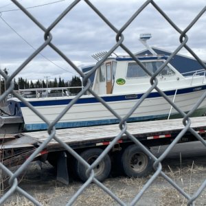 This is a 26? Fisherman I think they?re called, probably late 80s or 90s boat. Parked in the Alaska DOT lot in Ninilchik April 2024. I?ve seen others like this but not this boat, unless it maybe used to be in Seward. Has a AK charter fishing reg sticker. Possibly converted from an I/O given the metal bracket. Looked clean.