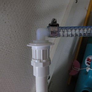 I drilled a hole in the cap and fit a nylon elbow into it from above.  It's 1/2" barb (hose end) to 1/2" male NPT (end that goes through the cap).  That threads into a PVC fitting that is 1/2" female NPT on top, and a meant-to-be-glued socket on the bottom that fits the OD of 1/2" PVC pipe.  No need to glue as it's a tight friction fit.