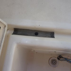 hole in drainage lip covered with screen to keep ou debris