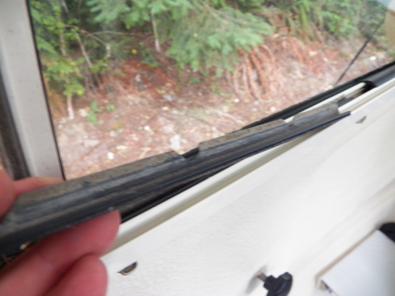 A grubby sliding strip showing why the C-Dory windows lose their slipperiness.  Installation is the reverse of removal, but getting the plastic strips to set back in right was time consuming.  They "click" in to place when everything is lined up properly.  The little tempered glass replacement was about $100 and took a couple of days.  The glass shop in Seattle had to send it out to get the right thickness of tempered glass cut with rounded corners.