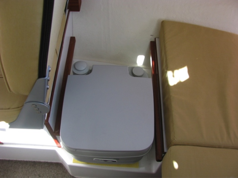 Another location for the portable toilet during the day.  We found it could also be nestled between the copilot seat and berth, but of course passengers would have to sit at the table.  Don't try this, however, when the top-level, fresh-water reservoir is full and the bottom container is empty.  This renders the toilet top heavy, and in the event of the boat healing sharply to starboard, it could tip over.  This could empty its contents onto the floor. (I know -- this happened to us.)  Since May, 2012, we no longer use this arrangement, and now favor the cockpit area with a larger porta potti.  (see related subfolders)