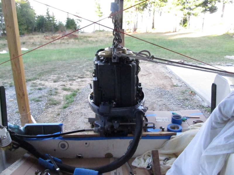 Another view of the engine hoisted.  The lines going off to port go to the stern cleat on that side and hold engine slightly to port, while I do starboard side holes.  Next I'll hold engine slightly to starboard and do port side holes.