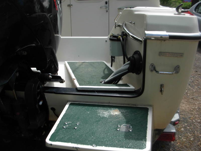 "Bridge over the splash-well from the swim step to the cockpit of boat.  3/4" plywood, epoxied & painted.  Green paint has sharp silica sand for traction.  Bridge must be kept slid to outside when boating.  You can see crunch on white edge where hydrolic steering arm crunched it when it moved too far to the center of the boat.  Note large "Sierra" fuel filter.  Filter which came with boat gave problems and left me to be towed in one time.  I replaced the original filter with this inexpensive one that still filters out water.  I replace filter canister yearly and no problem for last 6 years.