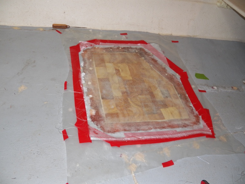 Here is the new core with two layers of glass cloth and Peel Ply release fabric over the whole repair.  Peel Ply allowed me to fair out the resin.  The surrounding exploratory holes and the bored out old pop rivet holes have all been filled with epoxy putty.  The mess is cleaned up.
