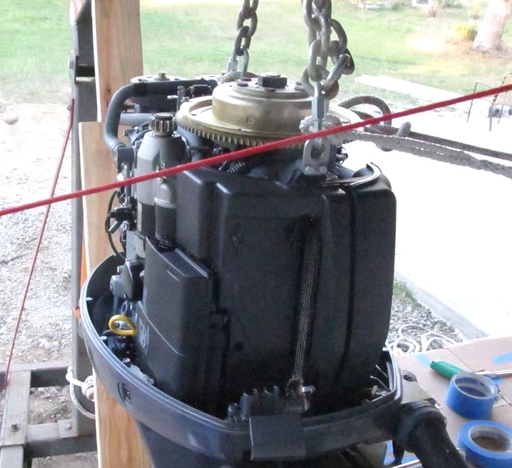 Here you can see the location of the lifting rings (they are always there on the engine just under a plastic sub-cowling that is fastened with two screws). You can also see where I had some (white) lines running from the rings over to the port side stern cleat to hold the engine slightly to one side so I could get tools in to work (was prophylactically epoxying transom holes). Ignore the red line in the foreground - that has nothing to do with the engine.