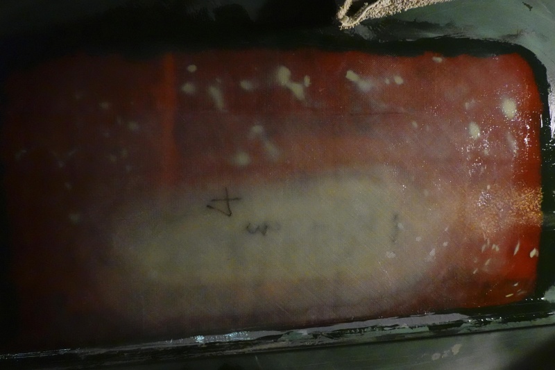 I sanded the paint off the patch and surrounding area and built up the area with epoxy resin and four layers of 1708 until the contour of the patch matched the surrounding area of the hull. The white spots are thickened eopxy under the glass, that I used to fill voids in the old repair (which will be removed from the top in the next step).