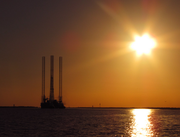 Oil rig moving down the ship channel at sunset