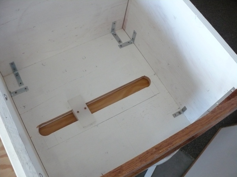 The Plastic "T" (made from cutting board) bolts down to/thru the floor. This keeps the seat box attached to the boat. Slide bolts hold the box in position, forward/aft side to side. A wood tray/cap goes over the "T", so it does not get in the way of gear storage. Or, if there is a drawer, the drawer will glide over the it. This system workes really well and is very simple to build.