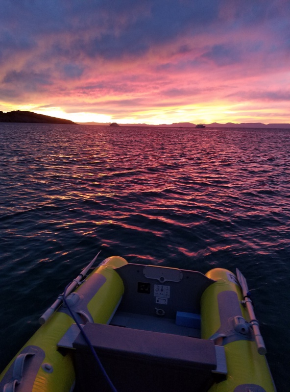 The start of a great sunset as the shrimp are on the barby. A couple of big superyachts anchored farther out and the mountains of Baja in the background.