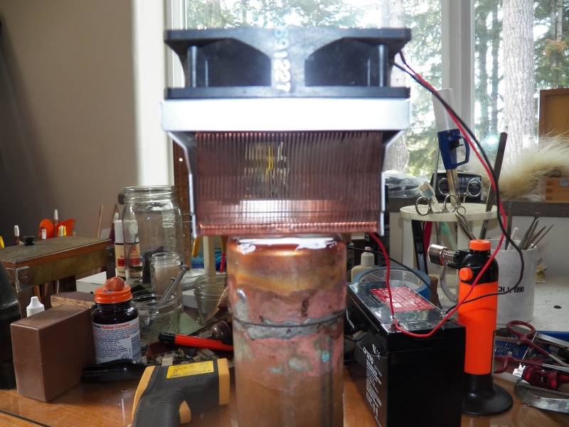 This is a thermo-electric chip (TEC) with an air cooled copper heat sink salvaged from a computer on top and a length of 1.5" copper pipe filled with antifreeze on the bottom.  It is stuck together with thermal epoxy.